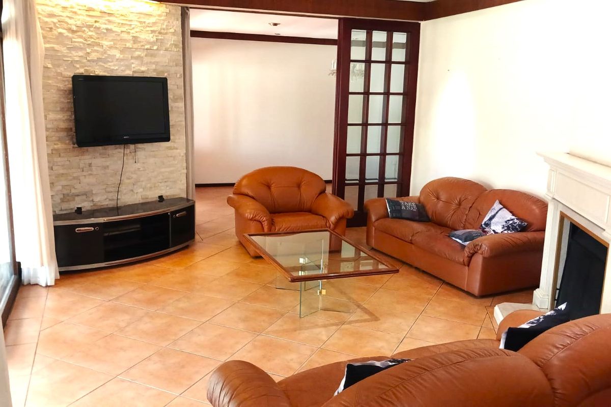 Spacious living room featuring a stone accent wall, fireplace mantel, and tiled flooring, with glass french doors leading to an adjacent area.
