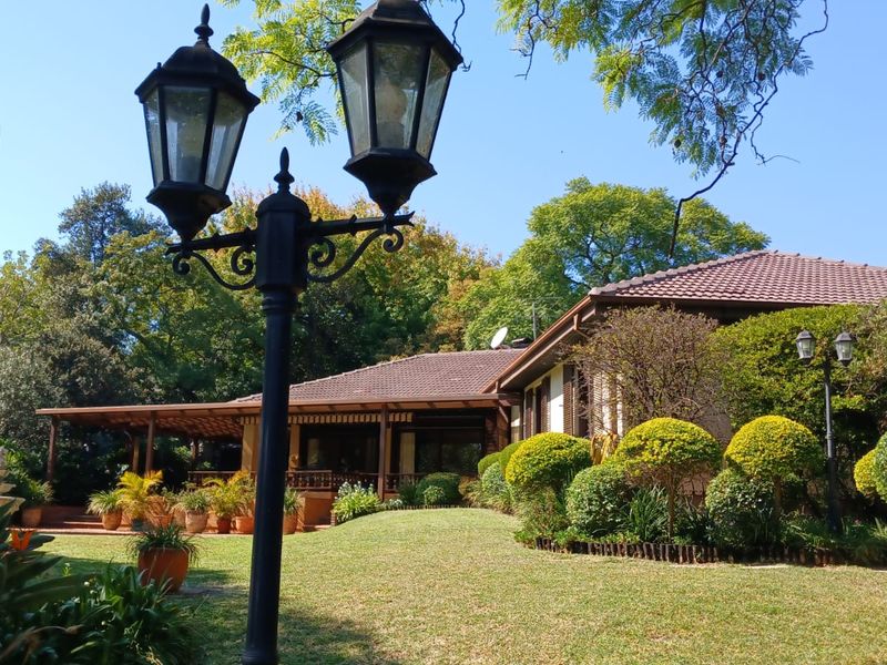 A well-maintained rear garden featuring a spacious covered patio, mature landscaping, and classic garden lighting, providing a serene outdoor living space.