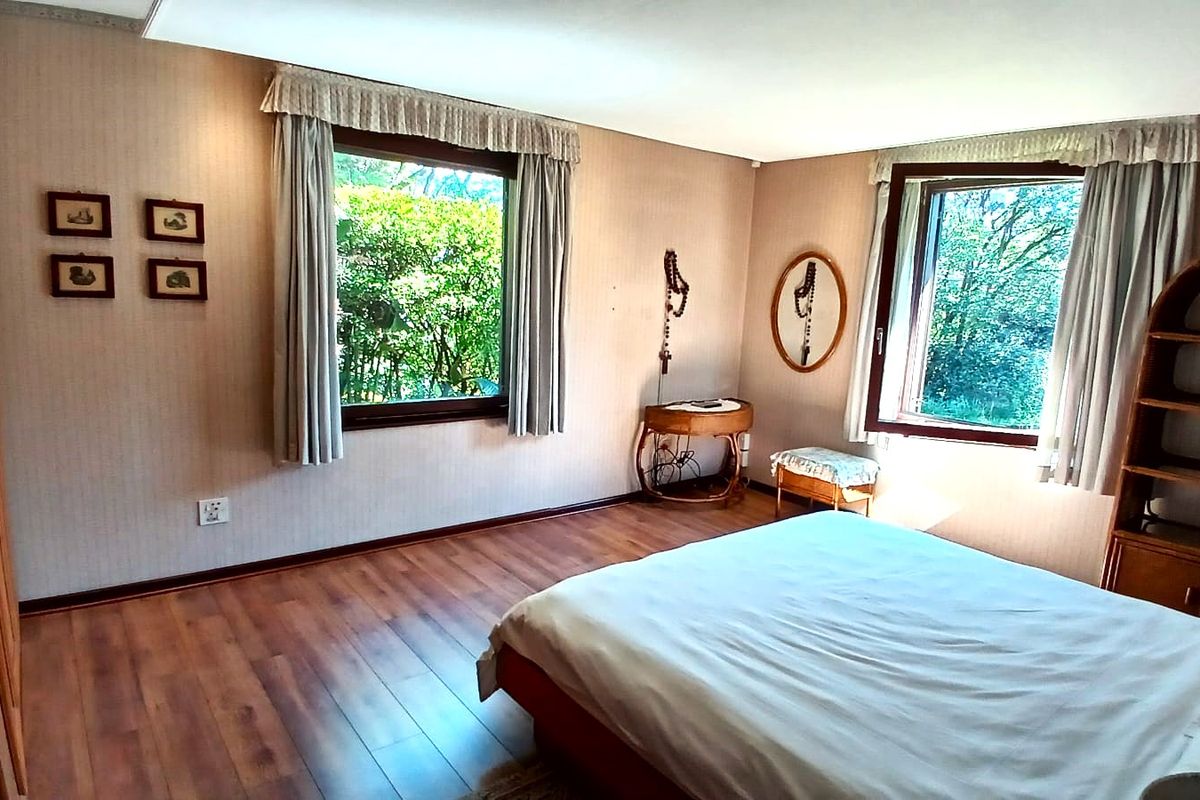 A spacious bedroom featuring laminate flooring, built-in wardrobes, and large windows that provide ample natural light and garden views.