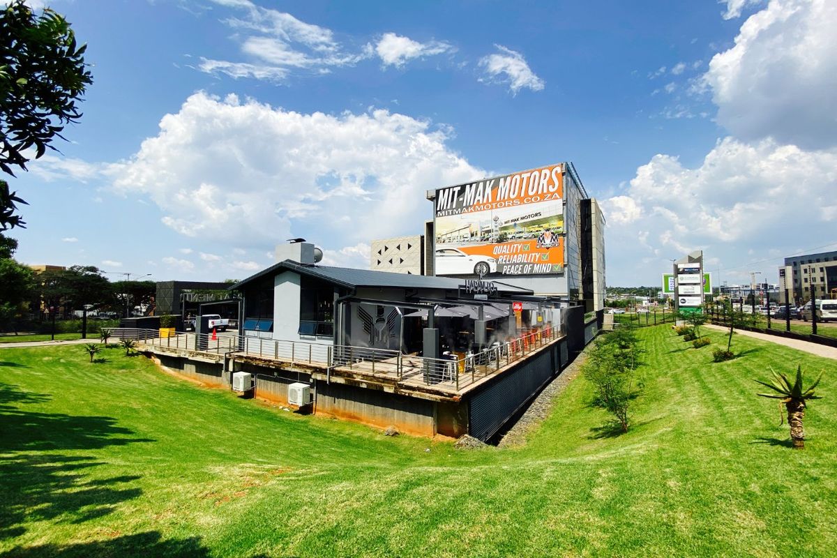 Rear view of a commercial property featuring a raised deck, metal roofing, and a prominent rooftop billboard advertisement.