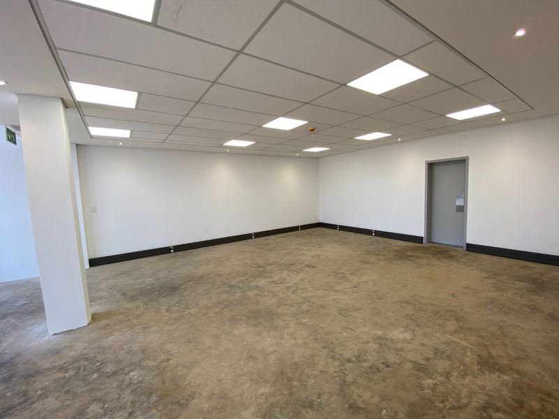 An open-plan industrial utility space featuring a suspended ceiling with recessed lighting and unfinished concrete flooring.