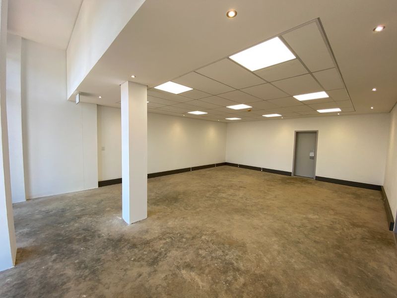 Spacious open-plan industrial unit featuring a suspended ceiling with recessed lighting, a central structural column, and durable concrete flooring.