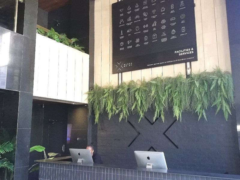 Modern reception area featuring a tiled service desk, timber-clad ceiling, and a prominent facilities information board.