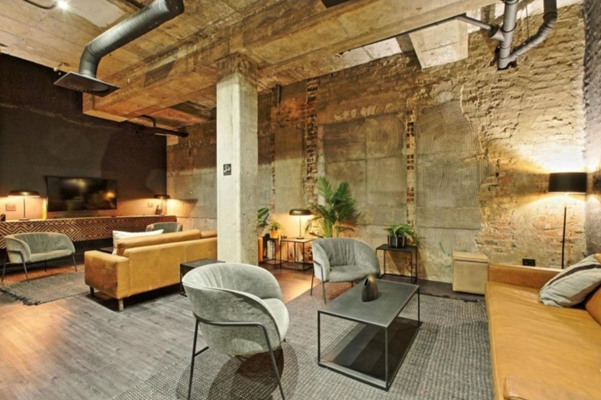 Industrial-style living room featuring exposed concrete ceilings, ductwork, and raw brick walls, creating a unique urban aesthetic.