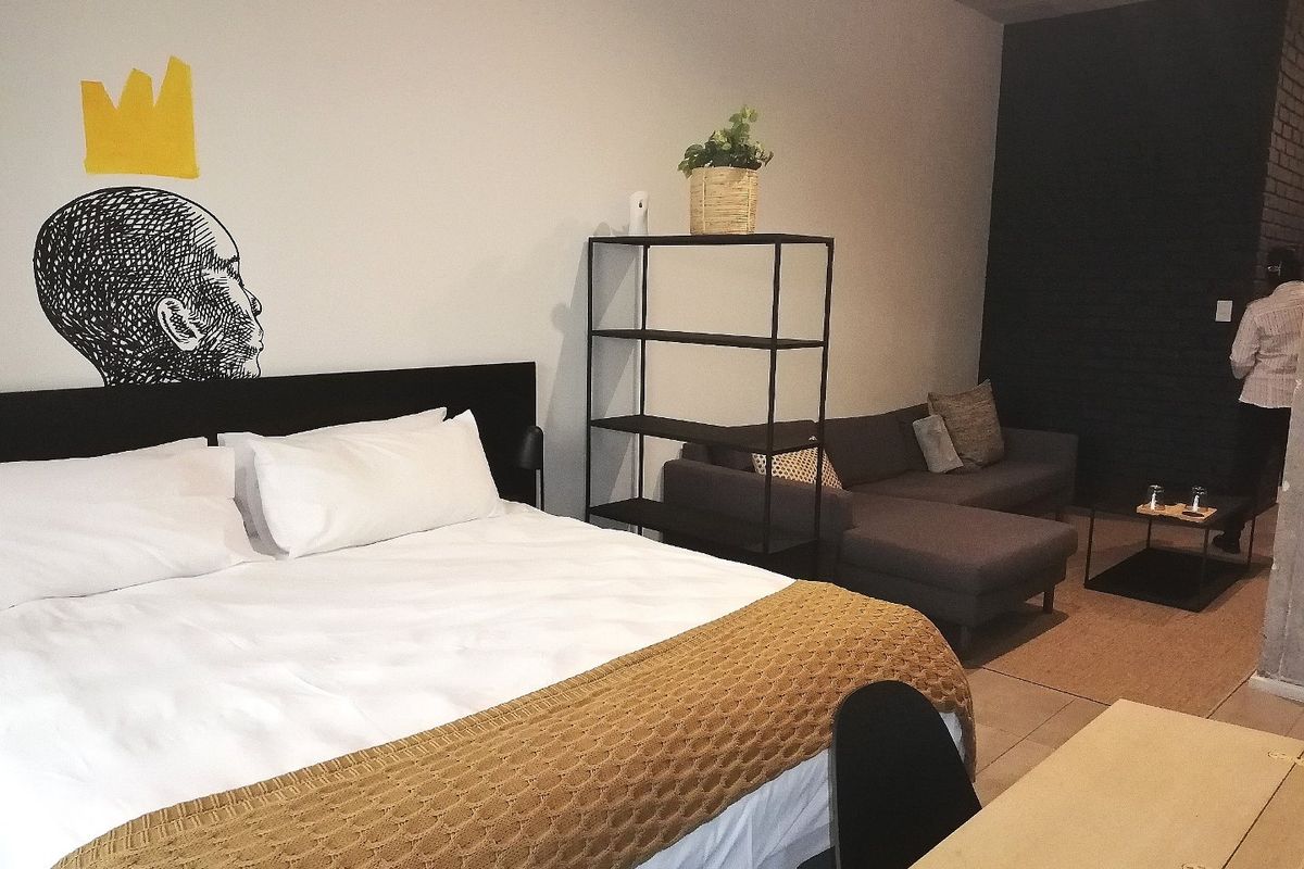 A spacious bedroom featuring tiled flooring and an exposed brick feature wall, offering a contemporary and comfortable living space.