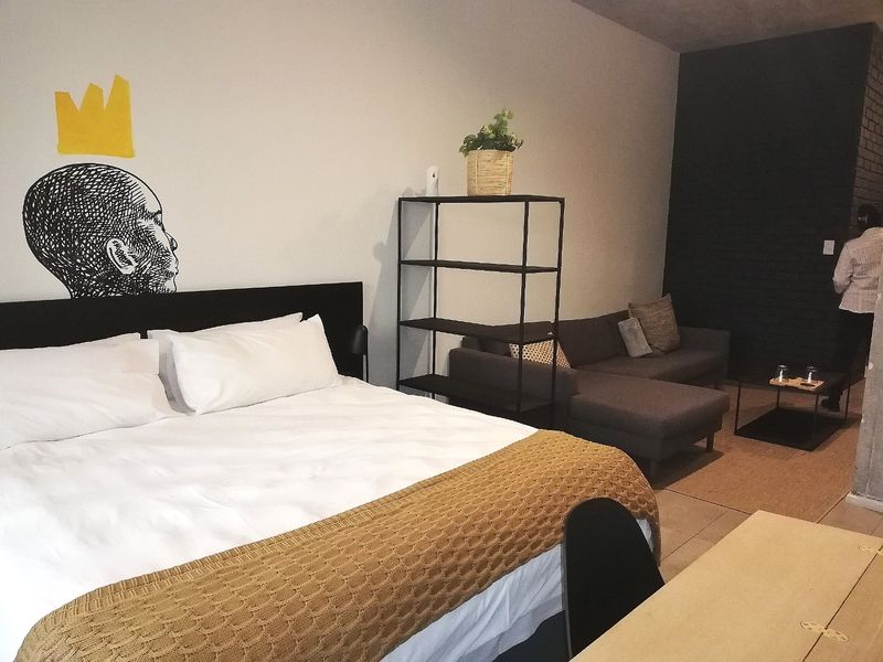 A spacious bedroom featuring tiled flooring and an exposed brick feature wall, offering a contemporary and comfortable living space.