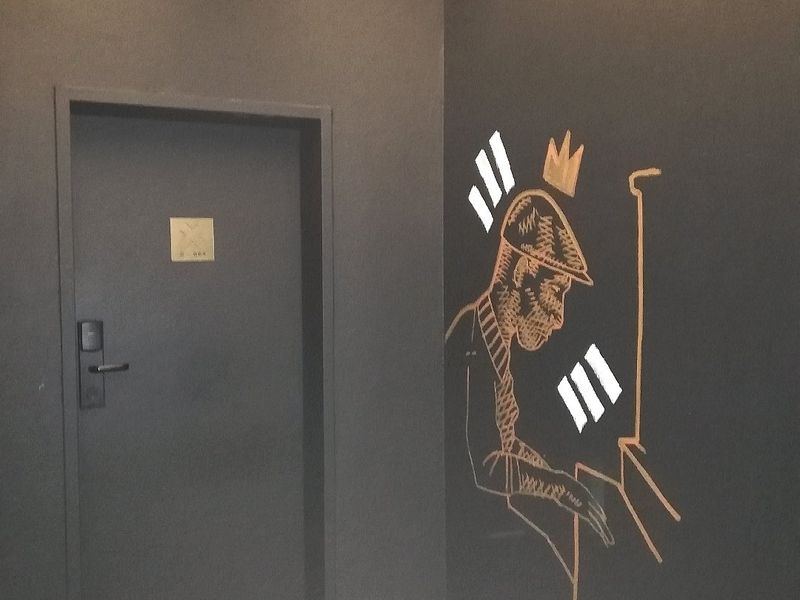 A modern hallway featuring dark painted walls with decorative mural art and a secure electronic door lock.