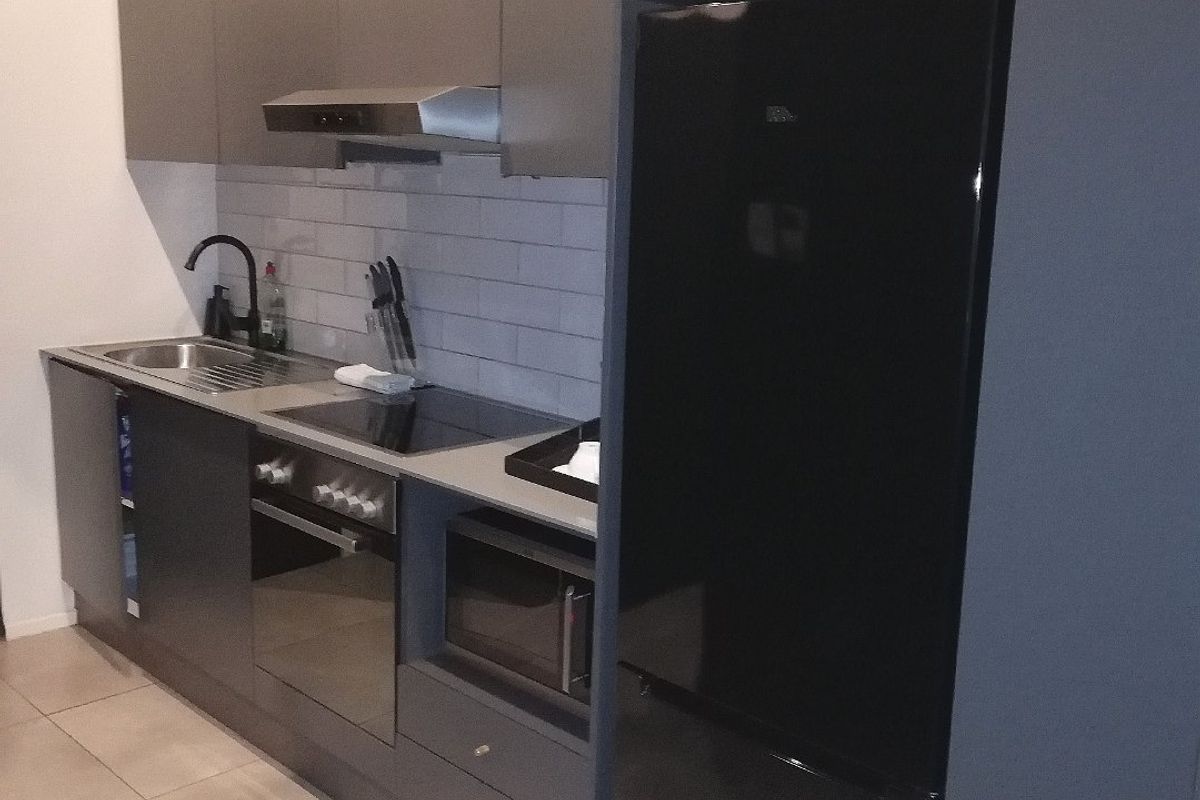 Modern kitchen featuring sleek dark cabinetry, integrated appliances, subway tile backsplash, and durable tiled flooring in a compact, efficient layout.