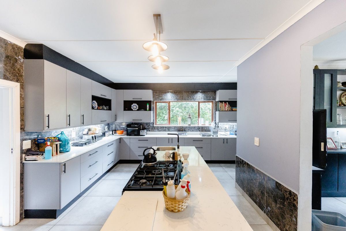 Modern kitchen featuring a central island with a built-in gas hob, stone countertops, and ample grey cabinetry with integrated storage solutions.
