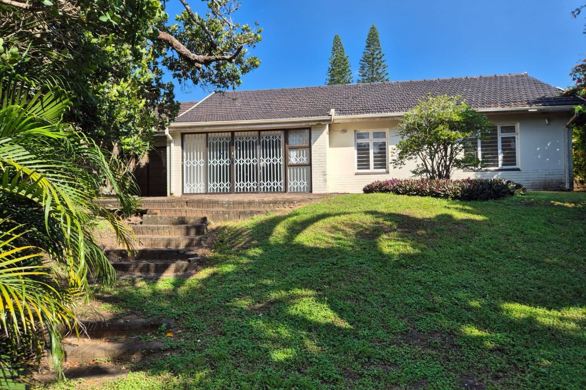 Rear view of the house featuring a brick patio area, concrete steps, and a spacious garden with established landscaping.