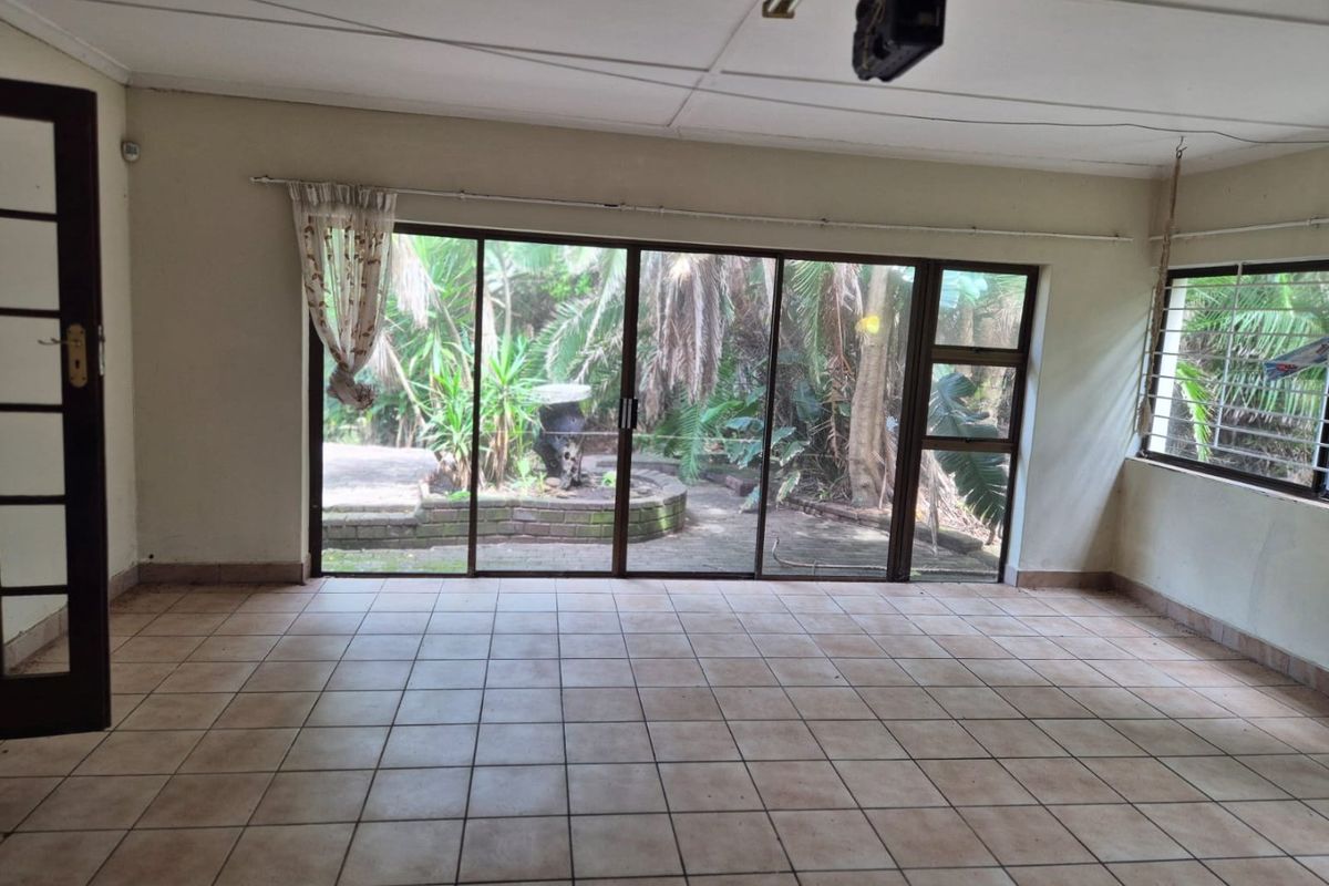 Spacious living area featuring large sliding glass doors that provide direct access to the garden and allow for ample natural light.