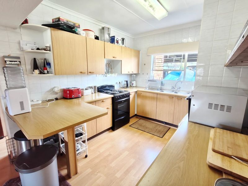 Functional kitchen featuring laminate cabinetry, ample counter space, a double basin sink, and a freestanding stove with tiled splashbacks.