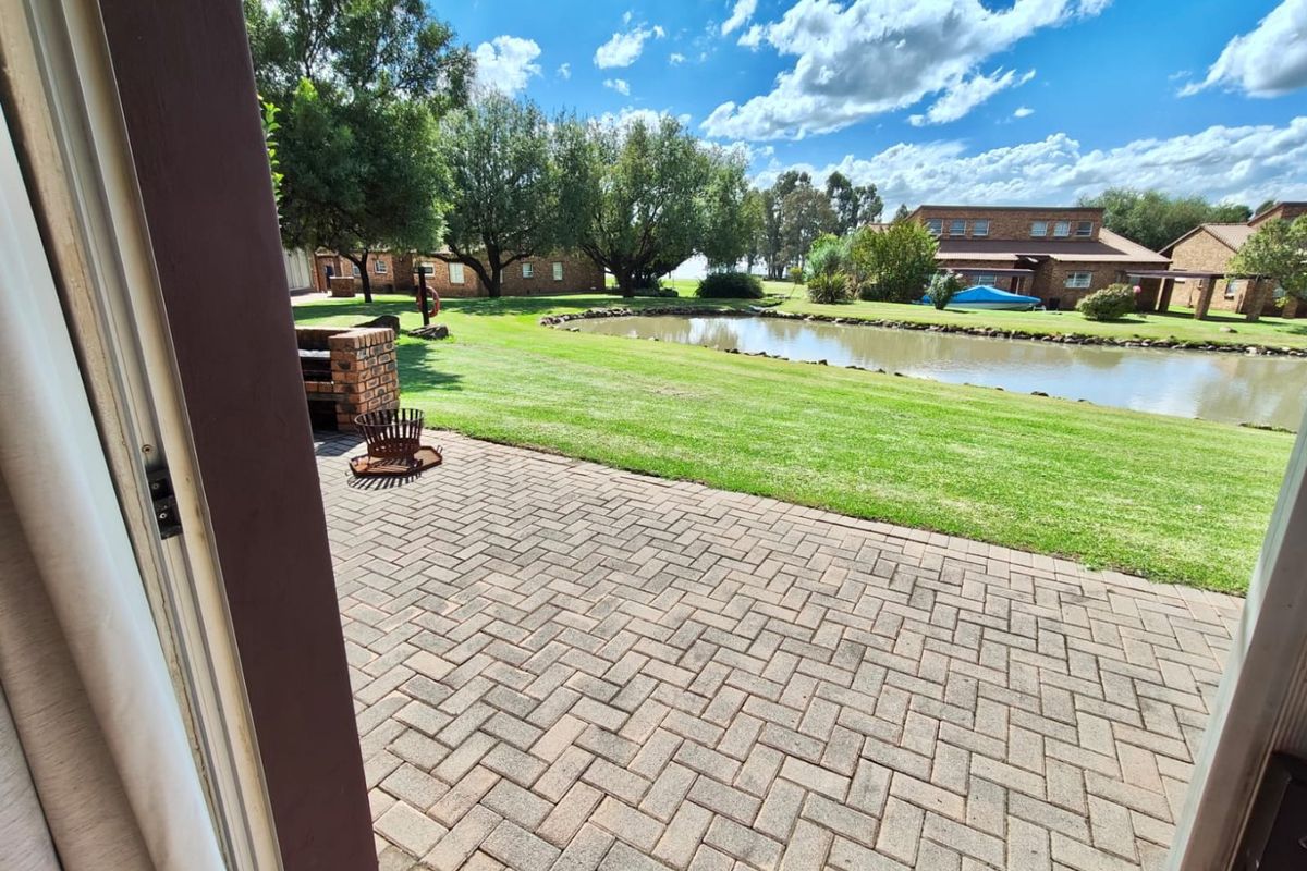 A view from the patio overlooking a well-maintained lawn, a small pond, and surrounding residential buildings.