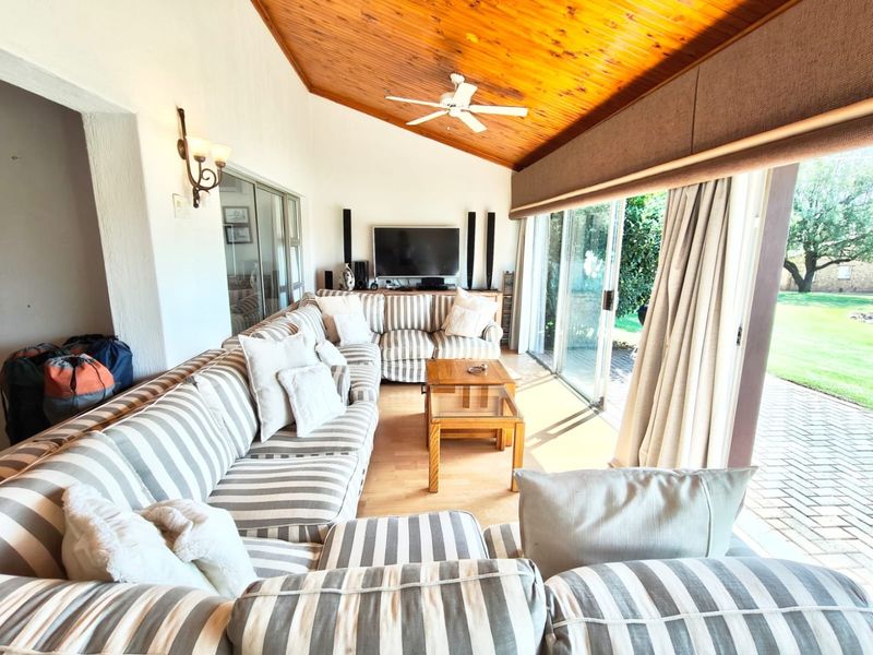 Spacious living room featuring a vaulted timber ceiling, ceiling fan, and large sliding glass doors that provide seamless access to the outdoor patio area.