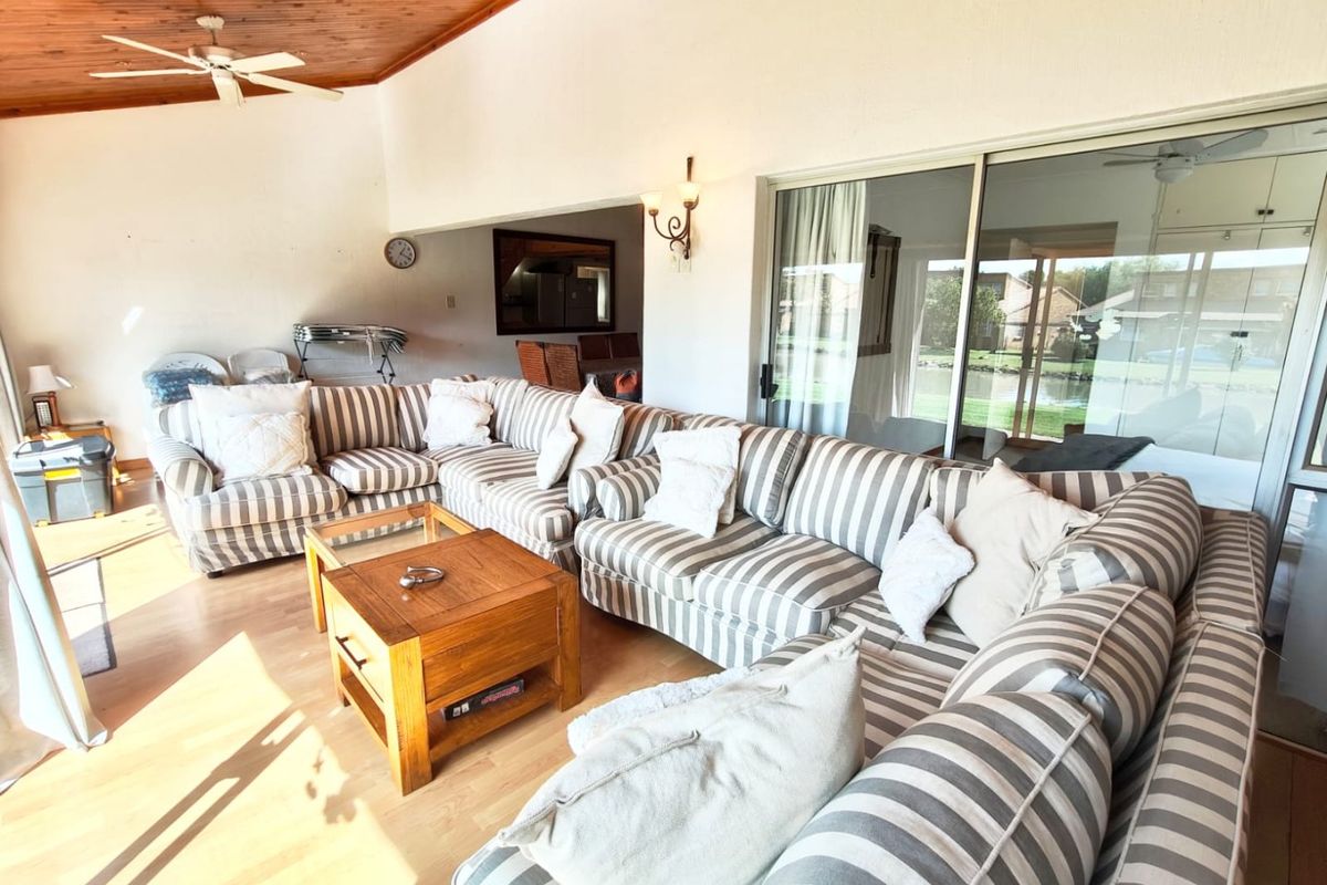 Spacious living area featuring a warm timber-clad ceiling, ceiling fan, and large sliding glass doors that provide ample natural light and access to the outdoors.