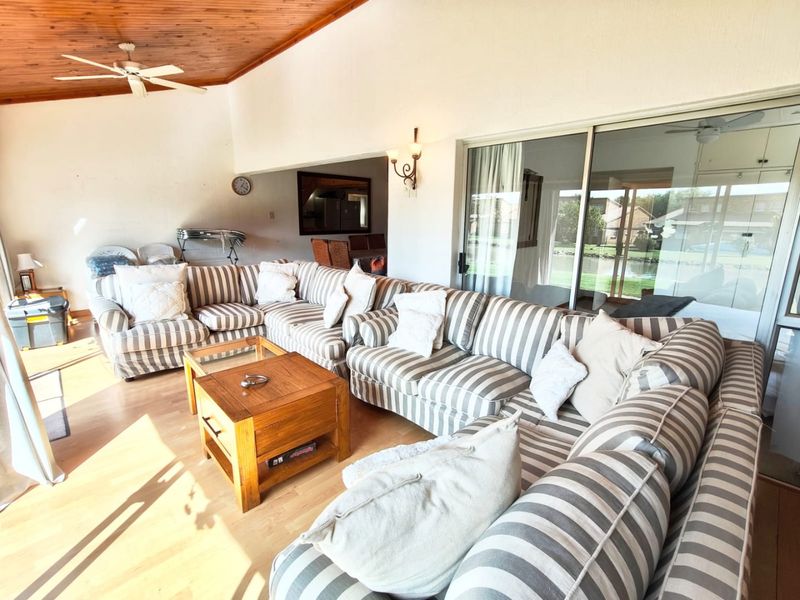 Spacious living area featuring a warm timber-clad ceiling, ceiling fan, and large sliding glass doors that provide ample natural light and access to the outdoors.