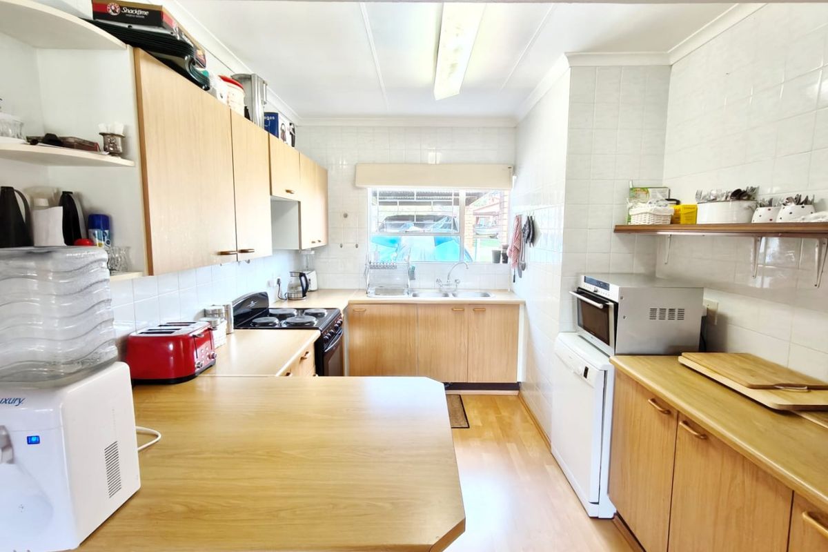 Functional kitchen featuring laminate cabinetry, ample countertop space, a double bowl sink, and a built-in oven with electric cooktop.