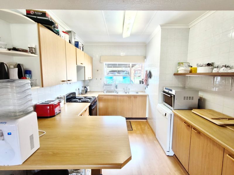 Functional kitchen featuring laminate cabinetry, ample countertop space, a double bowl sink, and a built-in oven with electric cooktop.