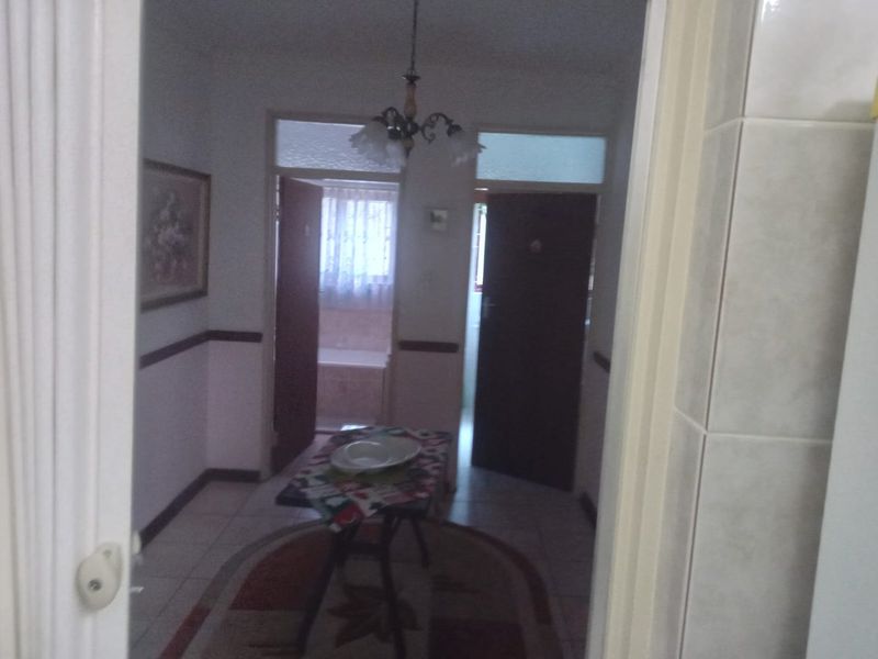 A functional hallway area connecting multiple rooms, featuring tiled flooring and a central ceiling light fixture.
