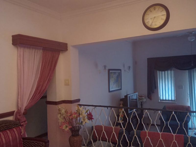 A split-level living area featuring tiled flooring, a decorative metal balustrade, and an ornate chandelier, providing a traditional layout with distinct living zones.