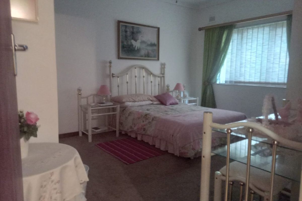 A carpeted bedroom featuring a window with curtains and a ceiling fan, offering a functional and lived-in space.