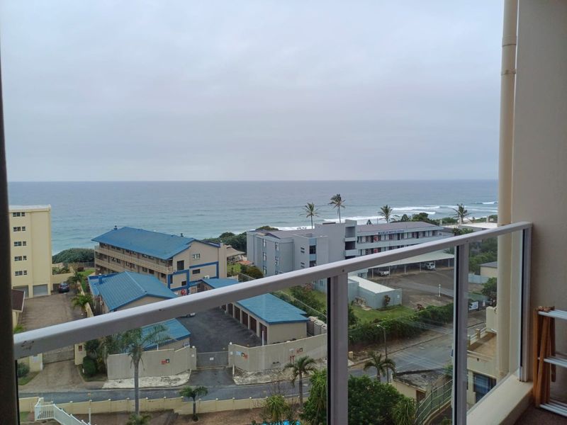 A balcony featuring a glass balustrade with clear views overlooking the surrounding coastal neighborhood and ocean.