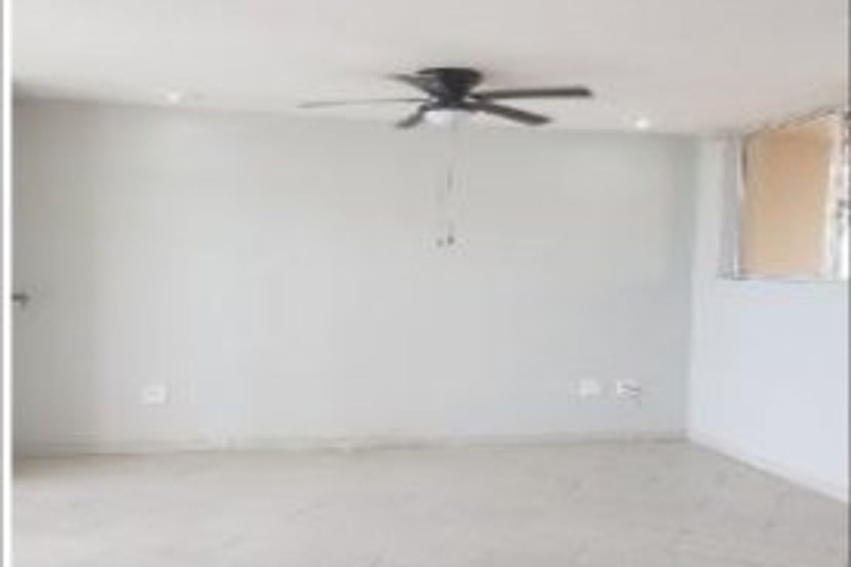 An empty, neutrally painted living area featuring tiled flooring, a ceiling fan, and recessed lighting.