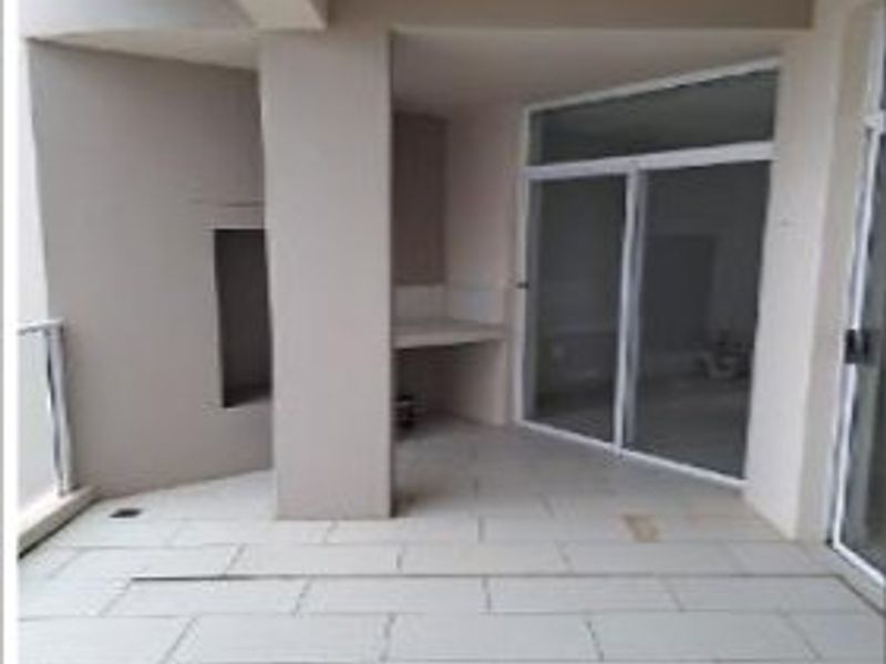 Covered balcony featuring tiled flooring, a built-in braai area, and sliding glass door access to the interior living space.