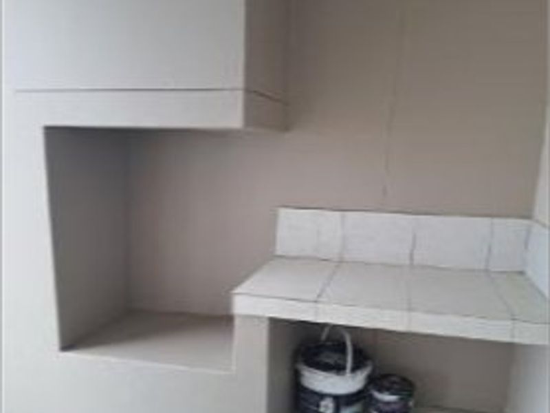 Outdoor patio area featuring a built-in braai and tiled preparation counter, requiring minor cosmetic repairs and maintenance.
