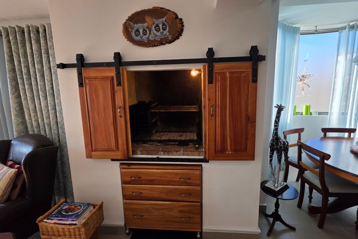A living area featuring a custom built-in indoor braai with sliding wooden barn doors and integrated cabinetry for storage.