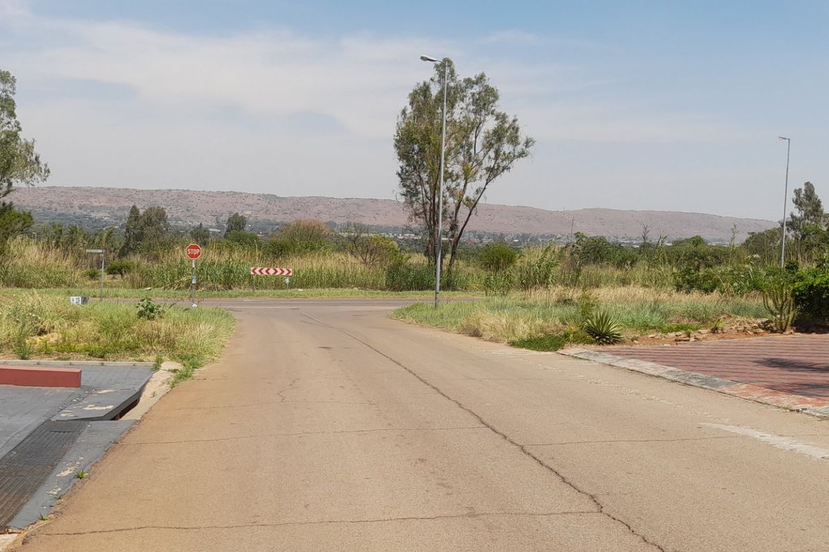 A view of the street approach and surrounding landscape, showing the paved road, access point, and natural vegetation of the vacant residential land.