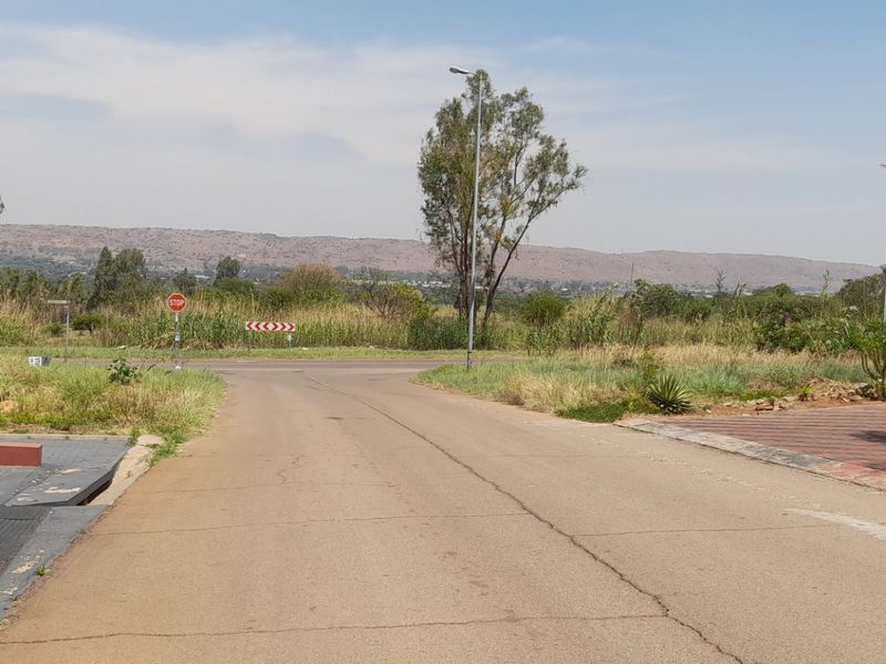 A view of the street approach and surrounding landscape, showing the paved road, access point, and natural vegetation of the vacant residential land.