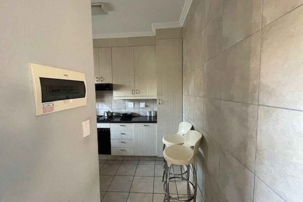A functional kitchen featuring built-in cabinetry, tiled flooring, and a tiled feature wall, equipped with a built-in oven and extractor fan.