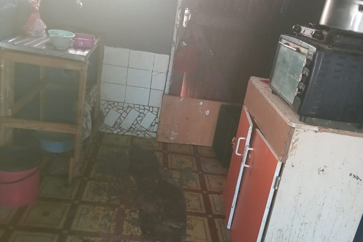 A small kitchen area featuring basic cabinetry and tiled splashback, currently showing significant wear and requiring maintenance or renovation.