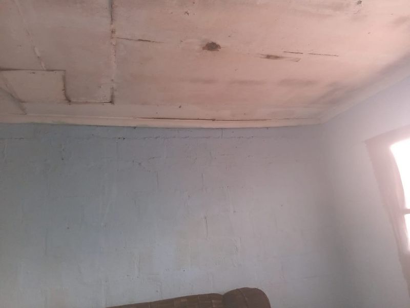 A bedroom interior showing significant ceiling damage and signs of moisture staining on the ceiling panels.