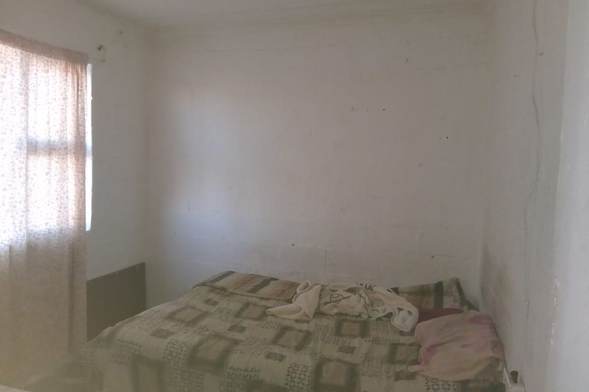 A simple bedroom featuring plain walls and a window, offering a blank canvas for potential renovation and interior design updates.
