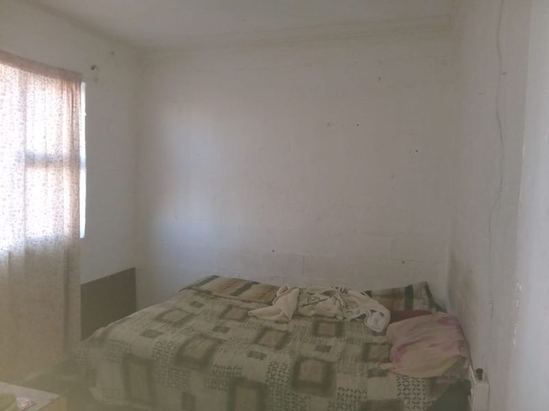 A simple bedroom featuring plain walls and a window, offering a blank canvas for potential renovation and interior design updates.