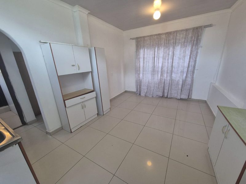 A functional kitchen area featuring tiled flooring, built-in cabinetry, and an arched entryway, offering a clean and neutral space ready for updates.