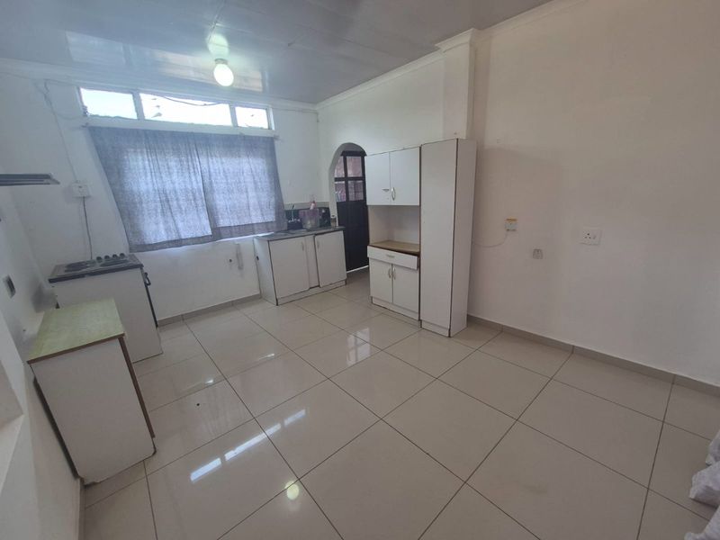 A functional, empty kitchen featuring tiled flooring, built-in white cabinetry, and a stove, offering a clean canvas for potential updates or modern styling.