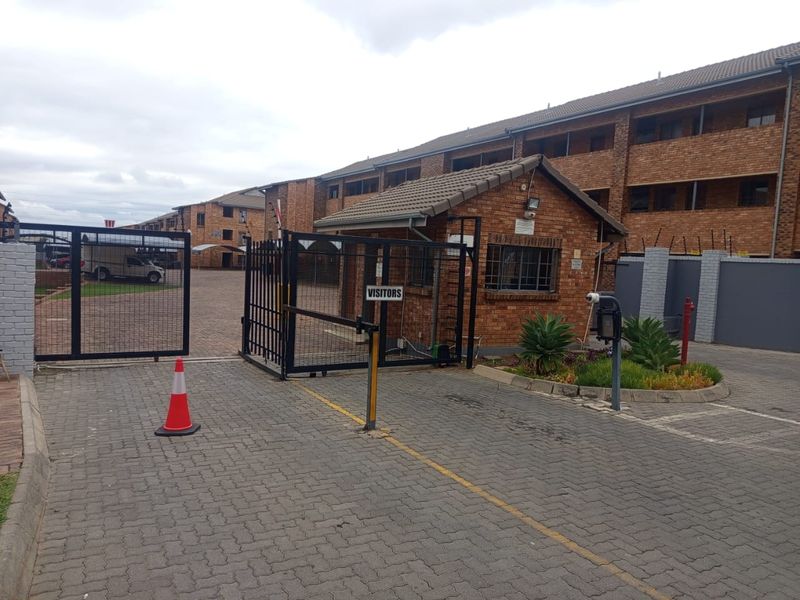 The property entrance features a secure gated access point with a brick guard house, paved driveway, and perimeter electric fencing.