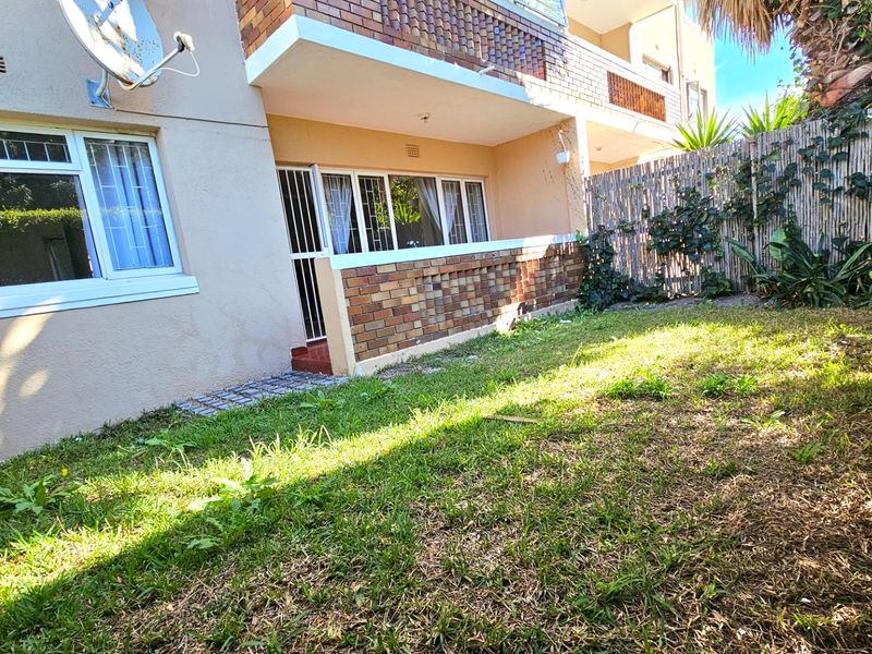 Rear exterior view of the apartment featuring a private garden area, brick facade, and security access points.