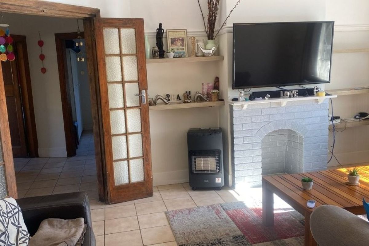 Living room featuring a painted brick fireplace, built-in shelving, and classic timber-framed glass panel doors leading to the hallway.