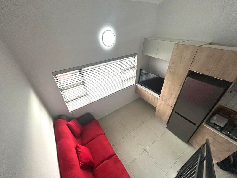 Compact open-plan living area featuring tiled floors, built-in cabinetry, and a functional kitchen layout with integrated storage.