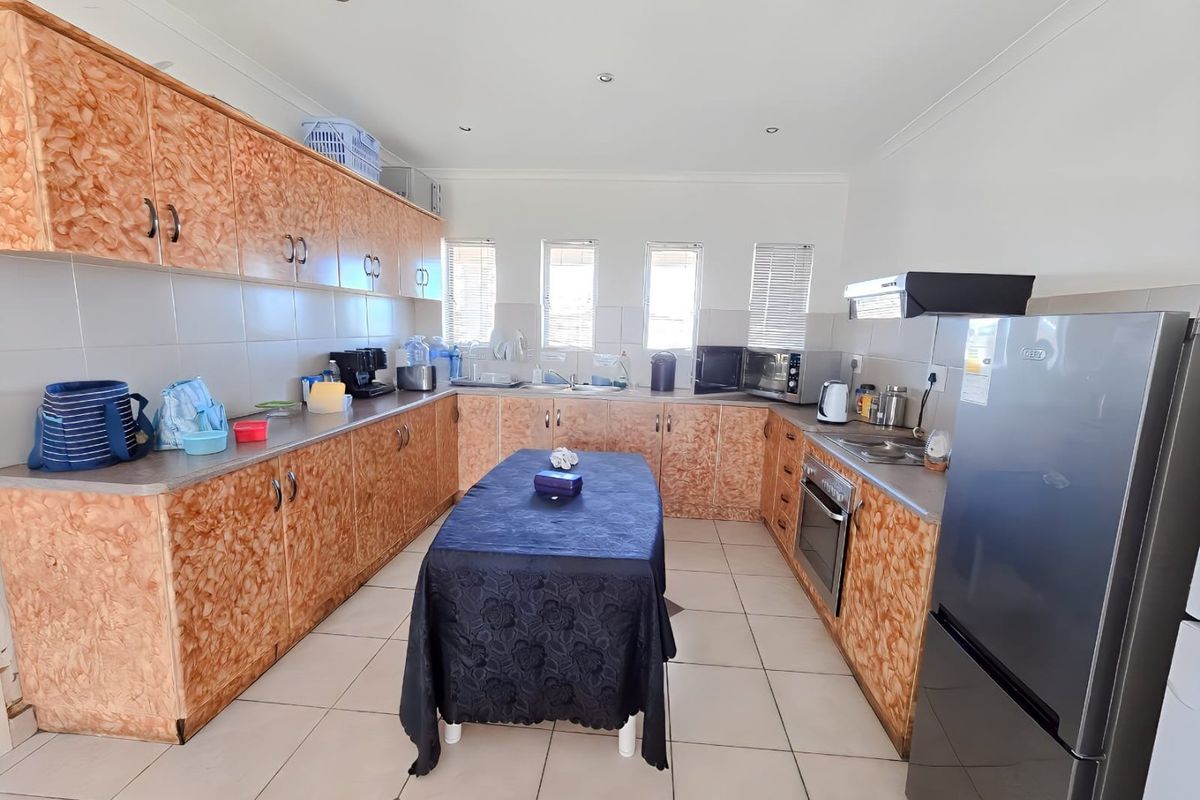 A functional kitchen featuring extensive laminate cabinetry, tiled flooring, a built-in oven, and an extractor fan with ample counter space.