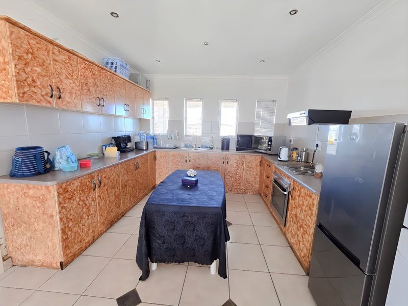 A functional kitchen featuring extensive laminate cabinetry, tiled flooring, a built-in oven, and an extractor fan with ample counter space.