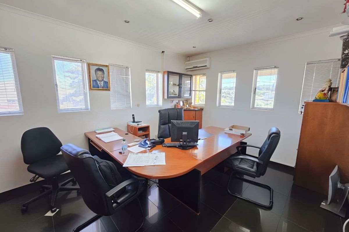 A functional office space featuring tiled flooring, multiple windows with venetian blinds, air conditioning, and integrated lighting fixtures.