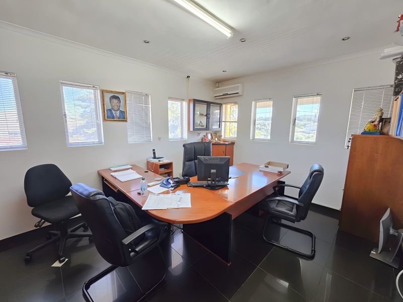 A functional office space featuring tiled flooring, multiple windows with venetian blinds, air conditioning, and integrated lighting fixtures.