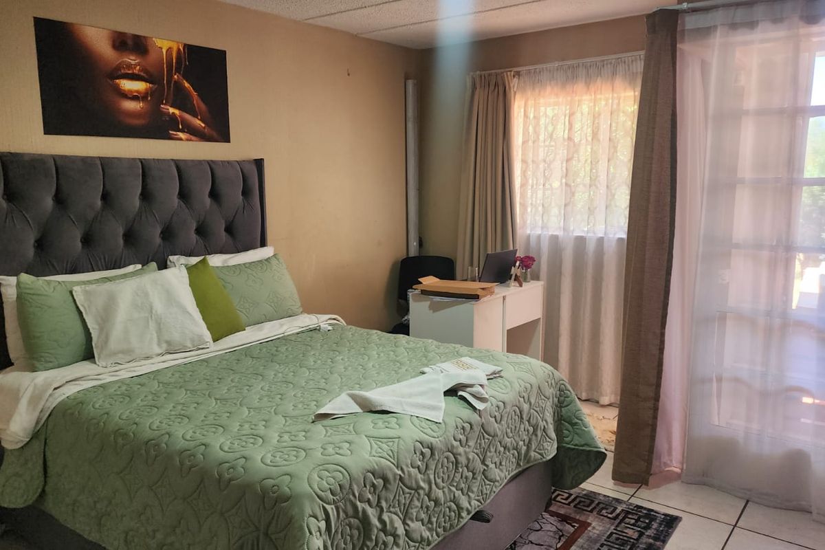 A bedroom featuring tiled flooring and direct access to an outdoor area through glass-paned french doors.