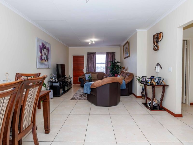An open-plan living and dining area featuring neutral tiled flooring and a coved ceiling, providing a functional and versatile space for daily living.