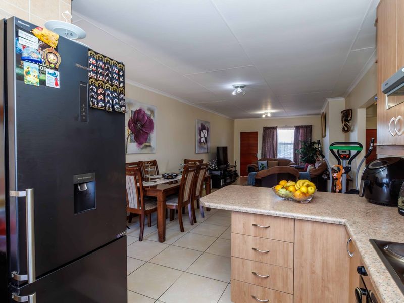 Open-plan living and dining area featuring tiled flooring and a functional kitchen with laminate cabinetry and countertops.